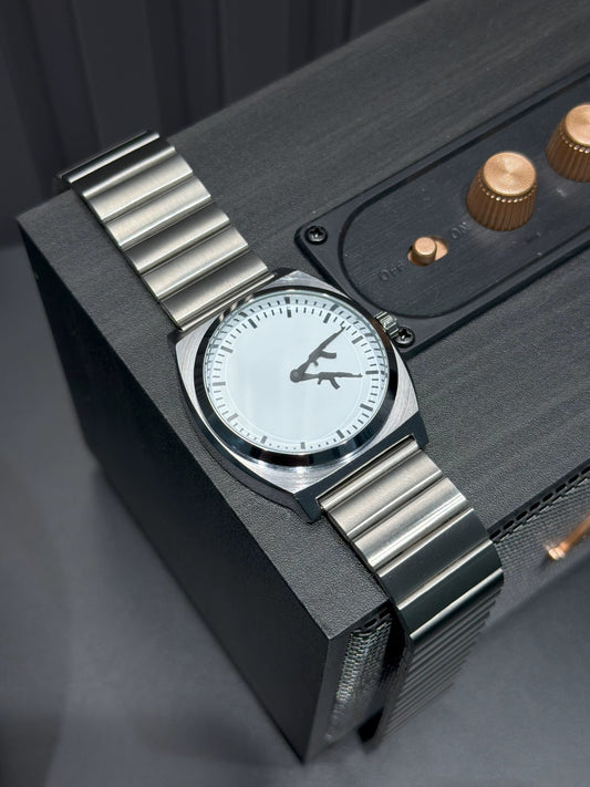 CHOOSZ Arcade Loadout watch with white dial and silver single-link steel bracelet draped over a black speaker