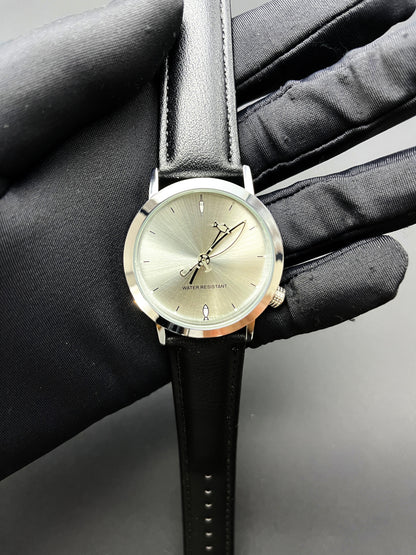 CHOOSZ Lucky Cast watch held in a black-gloved hand, showing its sunburst dial, fishing-themed hands and black leather strap