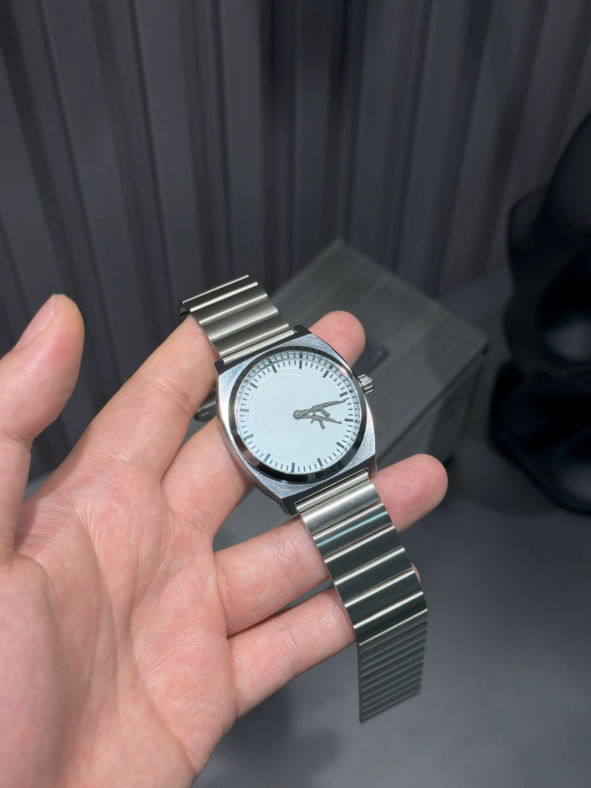 CHOOSZ Arcade Loadout watch held in a hand, showing its white dial, silver case and single-link steel bracelet