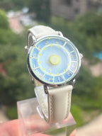 Astral Mythos zodiac watch held outdoors against green foliage