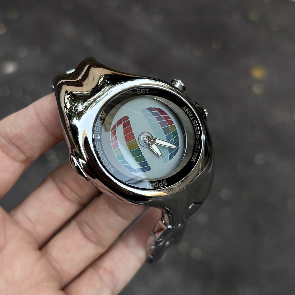 Morph Drift multicolor dial sculpted metal watch held outdoors