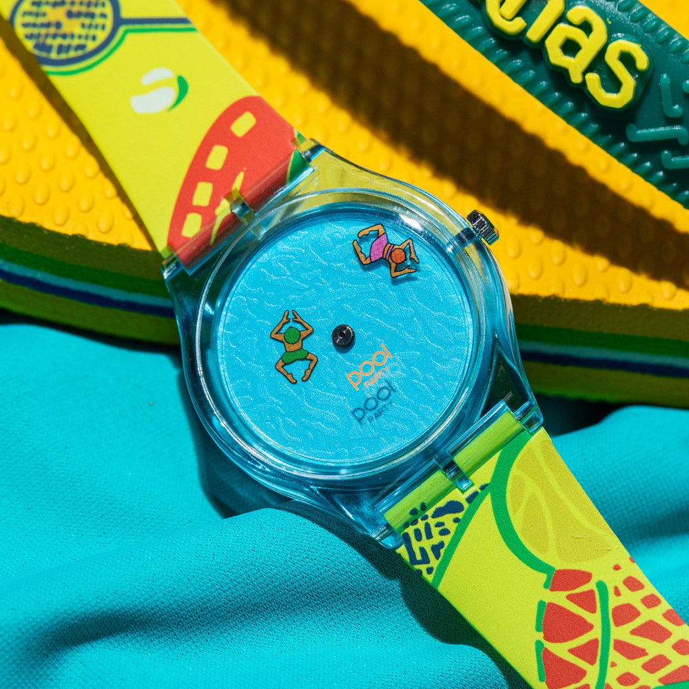 Pool Party aqua blue watch with neon fruit print strap styled beside colorful flip-flops