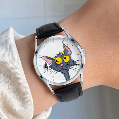 Chase Me, Kitty! white cat dial watch with yellow hands and black leather strap worn on a wrist beside a white cuff