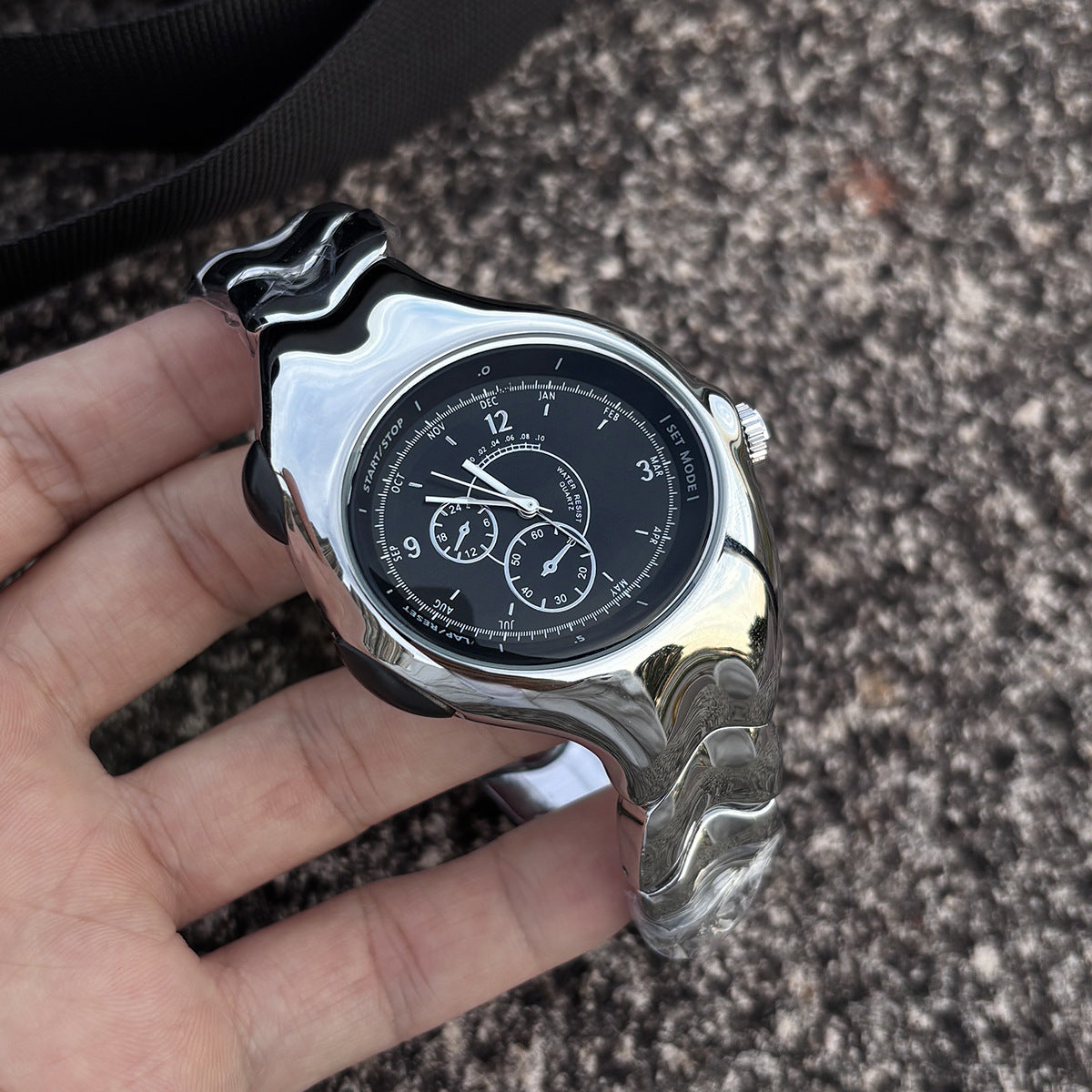 Chrono Flux black Y2K futuristic analog watch handheld close-up