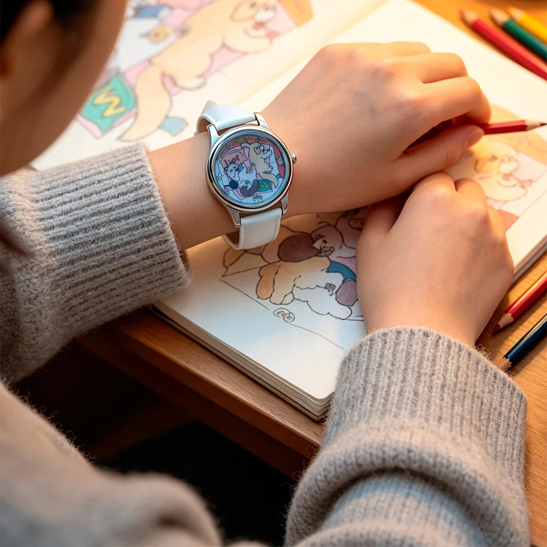 CHOOSZ Cozy Co-op watch with cartoon cat-and-dog dial and white leather strap worn while drawing in a sketchbook