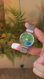 Nature's Orbit watch video showing the Sun hour and Moon minute indicators moving around the Earth landscape dial