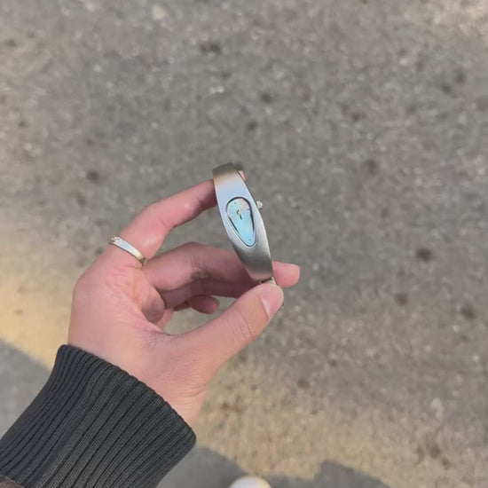 Mercury Drop Blue watch video showing the teardrop dial and sculptural metal case in outdoor sunlight