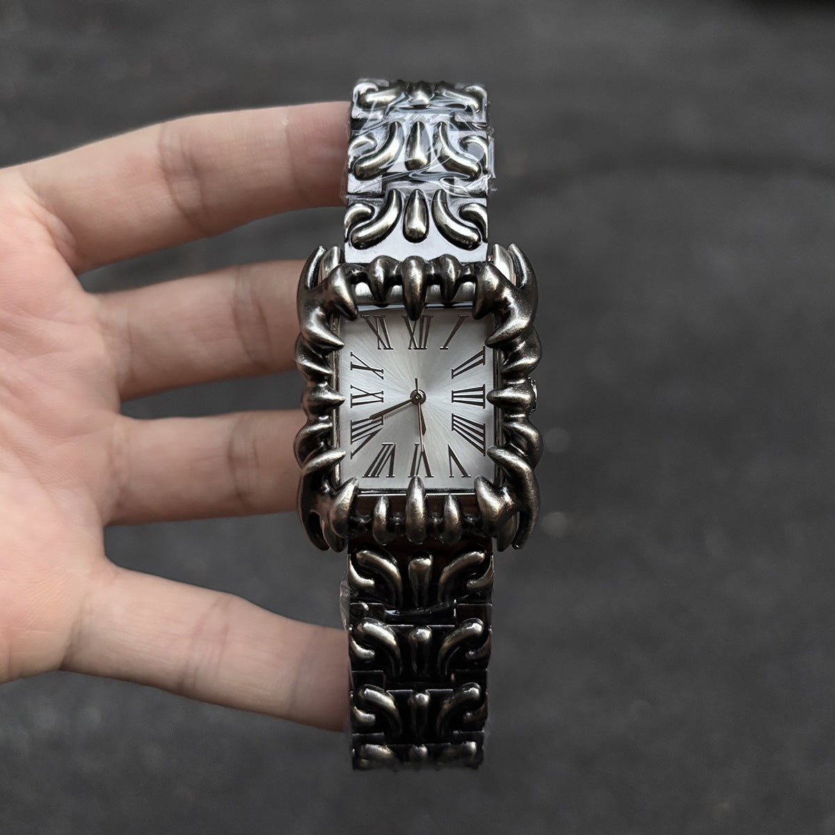 Abyss Grip silver dial gothic skeleton claw watch handheld close-up